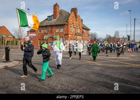 2023 St. Patrick's Day Parade in Orford Lane Warrington. Die irische Flagge führt die Prozession an, wenn sie die Straße überqueren Stockfoto