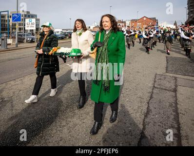 2023 St. Patrick's Day Parade in Warrington. Drei Damen tragen einen Kranz Stockfoto