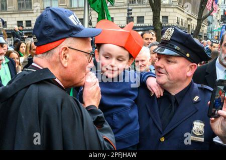 New York, USA. 17. März 2023. New York City Kardinal Timothy Dolan küsst die Hand des Sohnes eines Polizisten, nachdem er scherzhaft vor St. mit ihm Hüte getauscht hat Patrick's Cathedral während der St. Patrick's Day Parade am 17. März 2023. Etwa 150.000 Menschen marschieren jedes Jahr durch die Fifth Avenue in der größten St. Patrick's Day Parade, die seit 1762 jährlich stattfindet, um das irische Erbe zu feiern. Kredit: Enrique Shore/Alamy Live News Stockfoto