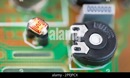 Nahaufnahme eines schwarzen Widerstandstrimmers oder Fotoresistors mit empfindlicher Oberfläche in einer grünen Leiterplatte. Kleine elektrische Bauteile auf verschwommener Leiterplatte. Stockfoto