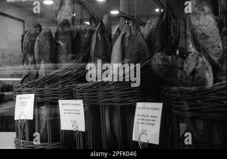 Baguettes mit frischem Brot in Körben im Fenster einer französischen Bäckerei in Melrose, Massachusetts. Das Bild wurde mit analogen Schwarz- und W-Bildern aufgenommen Stockfoto