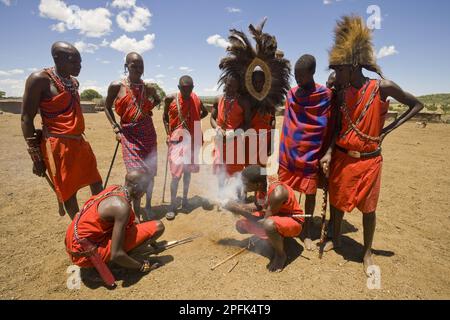 Maasai-Stammesangehörige zünden Feuer am Rande des Dorfes an, Masai Mara, Kenia Stockfoto