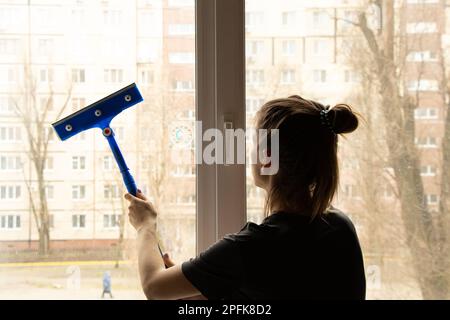 Das Mädchen wäscht das Fenster in der Wohnung und putzt Stockfoto