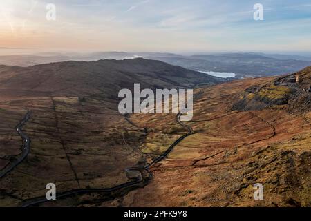 Luftbild einer Drohne mit Blick auf den Sonnenaufgang, Winterblick von Red Screes im Lake District mit Blick auf Windermere in der Ferne über Wansfell Pike Pea Stockfoto