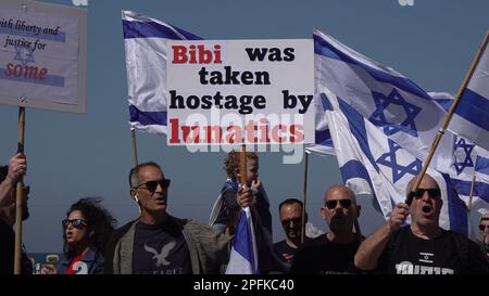 TEL AVIV, ISRAEL - MÄRZ 16: Ein Protestteilnehmer hält ein Schild mit der Aufschrift "Bibi wurde als Geisel von bt-Verrückten genommen" während einer Demonstration, die von regierungsfeindlichen Demonstranten vor der US-Botschaftsabteilung veranstaltet wurde und in der die US-Regierung aufgefordert wurde, sich gegen die neue rechtsgerichtete Koalition des israelischen Ministerpräsidenten Benjamin Netanjahu und die von ihr vorgeschlagenen gerichtlichen Änderungen im März zu stellen 16, 2023 in Tel Aviv, Israel. Kredit: Eddie Gerald/Alamy Live News Stockfoto