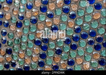 Nahaufnahme des Mosaikhintergrundes von runden glasblauen türkisfarbenen Kugeln in der Wand Stockfoto