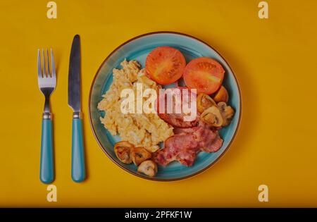 Warmes Frühstück mit Rührei auf gelbem Hintergrund. Stockfoto