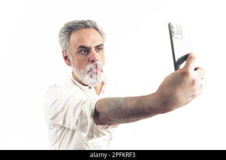 Ein grauhaariger Kaukasier macht ein Selfie mit Grimace - ein isoliertes Studio im Hintergrund. Hochwertiges Foto Stockfoto