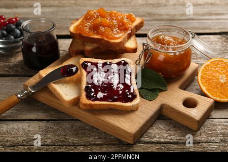 Köstliche Toasts mit Marmelade und Obst auf einem Holztisch Stockfoto