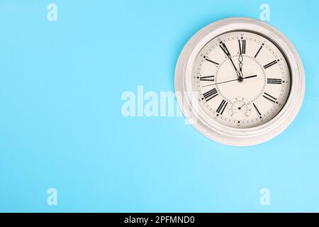 Stilvolle Wanduhr im Vintage-Stil mit fünf Minuten bis Mitternacht auf türkisfarbenem Hintergrund, Draufsicht mit Platz für Text. Der Countdown für das neue Jahr Stockfoto