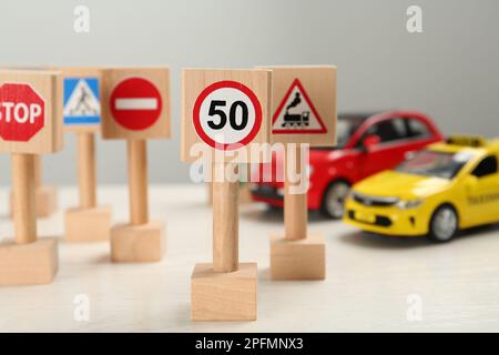 Miniaturschilder und Autos auf dem weißen Tisch. Fahrschule Stockfoto