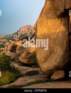 Wunderschöne Aussicht auf die mit Felsen übersäte Landschaft und Ruinen im Hampi. Hampi, die Hauptstadt des Vijayanagar Empire, gehört zum UNESCO-Weltkulturerbe. Stockfoto