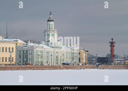 SANKT PETERSBURG, RUSSLAND - 06. MÄRZ 2023: Blick auf das antike Gebäude der Kunstkamera und die südliche Rostralsäule an einem wolkigen Tag im März Stockfoto