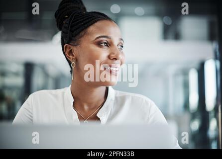 Behalten Sie das Sehvermögen jederzeit im Auge. Eine attraktive junge Geschäftsfrau, die allein in ihrem Büro sitzt und ihren Laptop benutzt. Stockfoto