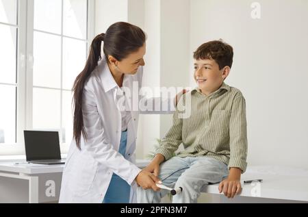 Arzt-Neuropathologe mit Spezialhammer untersucht Kniefehler bei Beinjungen. Stockfoto