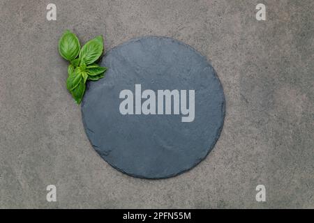 Leere Pizzaplatte für selbstgebackenes Backen auf dunklem Beton aufgesetzt. Food Rezept Konzept auf dunklen Stein Hintergrund Textur mit Kopierraum. Stockfoto