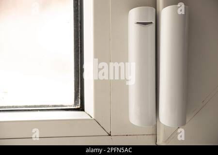 Sensor zum Öffnen des Fensters hängt am Fenster, Hausalarmierungssystem, Hausschutz, Hausalarm Stockfoto