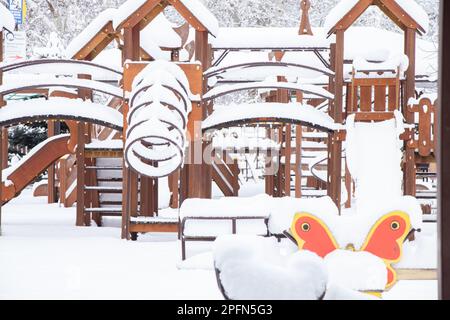 Kinderschaukel im Winter in einem Park im Schnee in der Ukraine in der Stadt Dnipro, Winter in der Stadt Stockfoto