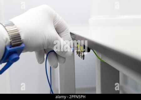 Erdungsarmband an der Hand mit ESD-Stoff auf grauem Hintergrund. Antistatisches ESD-Armband oder Erdungsarmband ist ein antistatisches Gerät zur sicheren Stockfoto