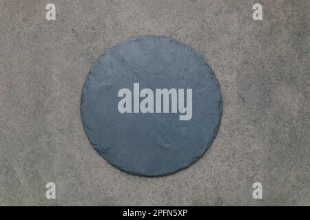 Leere Pizzaplatte für selbstgebackenes Backen auf dunklem Beton aufgesetzt. Food Rezept Konzept auf dunklen Stein Hintergrund Textur mit Kopierraum. Stockfoto