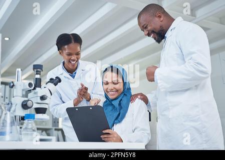 Sie haben einen weiteren fundamentalen Durchbruch gemacht. Eine Gruppe von Wissenschaftlern, die während der Arbeit in einem Labor jubeln. Stockfoto