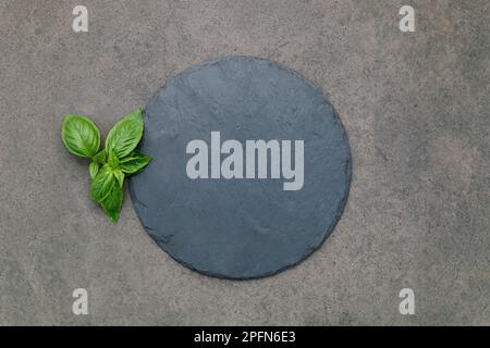 Leere Pizzaplatte für selbstgebackenes Backen auf dunklem Beton aufgesetzt. Food Rezept Konzept auf dunklen Stein Hintergrund Textur mit Kopierraum. Stockfoto