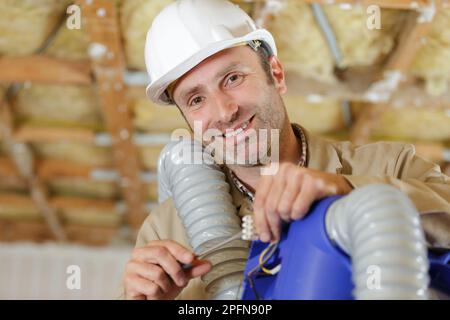 Zufriedener Arbeiter mit Lüftungsanlagen in der Hand Stockfoto