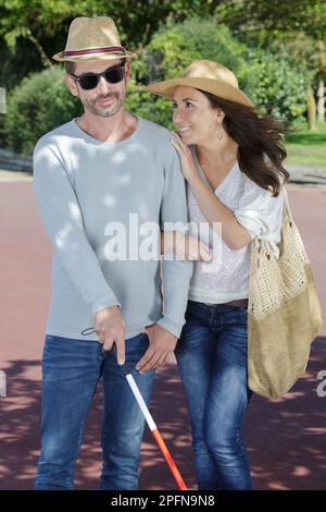 Blinder Mann und Frau, die im Park spazieren gehen Stockfoto