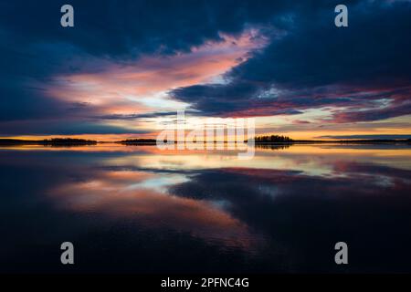 Herrliches Morgenlicht über dem Malarsee in Schweden, Reflexion im ruhigen Himmel mit dramatischen bunten Wolken, Goldener Horizont mit dunkler Silhouette Stockfoto