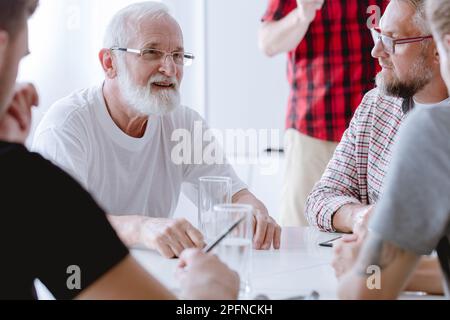 Grauer Senior Therapeut mit problematischem Patienten während der Beratung Stockfoto