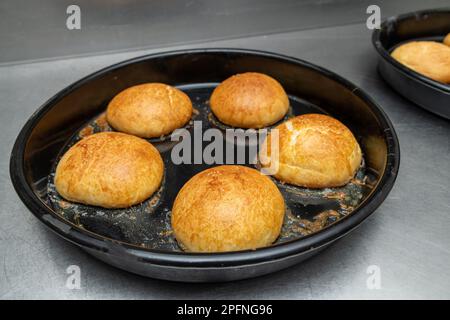 Frisch gebackene heiße Burger-Brötchen in einem Industrieofen Stockfoto