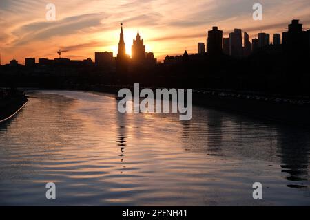 Stadtlandschaft mit Moskau Fluss, Ufer und Silhouetten von Gebäuden und Kreml Türmen bei wunderschönem Sonnenuntergang Stockfoto