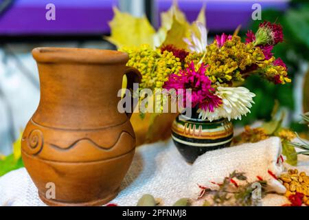 Herbststille. Herbstgeschenke. Ukrainischer Tonkrug mit Milch und Herbstblumen in einer Vase. Stockfoto