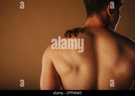 Nahaufnahme eines Mannes im Studio mit Tarantel auf dem Rücken Stockfoto