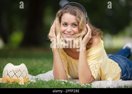 Junge Frau genießt das Liegen auf dem grünen Gras Stockfoto