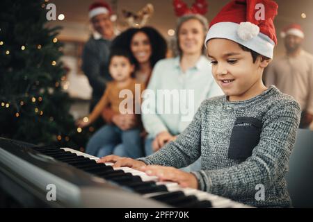 Junge, Musiktastatur und weihnachten im Familienhaus mit Lächeln, Spielen und kreativer Freude. Kind, junger Musiker und Eltern am Klavier Stockfoto