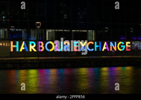 Ein beleuchtetes Schild für den Harbour Exchange Complex am Millwall Inner Dock im South Quay-Gebiet der Isle of Dogs in Docklands im Osten Londons. Stockfoto