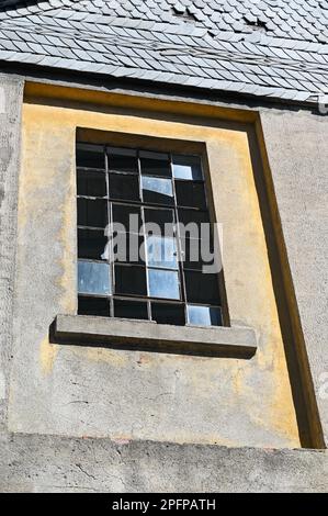 Fassade eines alten Hauses mit Metallgitterfenstern und zerbrochenen Glasscheiben in einem alten leerstehenden Gebäude Stockfoto