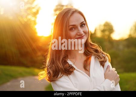 Süßes blondes Mädchen im Hintergrund der Sonne. Gewöhnliche glückliche Frau, die das Leben im Sommer genießt. Selbstbewusster Mensch Stockfoto