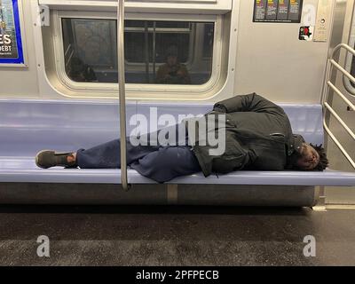 Ein Obdachloser schläft morgens in einem U-Bahn-Wagen in Manhattan in Brooklyn, New York. Stockfoto