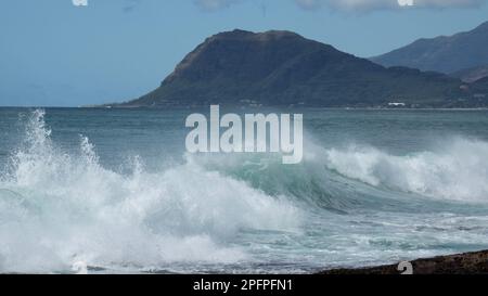 Wellen brechen vor den Lagunen von Ko Olina an der leeward Coast von Oahu ab, mit der Waierivanae-Gebirgskette im Hintergrund. Stockfoto