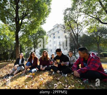 Peking/Moskau. 18. März 2023. Melchakova Nataliia (3. l) genießt einen Moment, während eine ihrer Klassenkameraden Gitarre an der East China Jiaotong University in Nanchang, Ostchina, Provinz Jiangxi, spielt, 31. Oktober 2019. Kredit: Hu Chenhuan/Xinhua/Alamy Live News Stockfoto