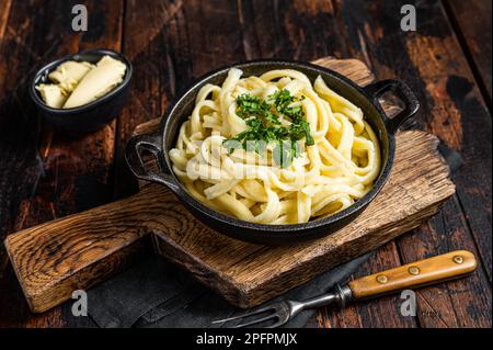 Deutsche Spaetzle-Eiernudeln mit Butter und Petersilie in einer Pfanne. Holzhintergrund. Draufsicht. Stockfoto