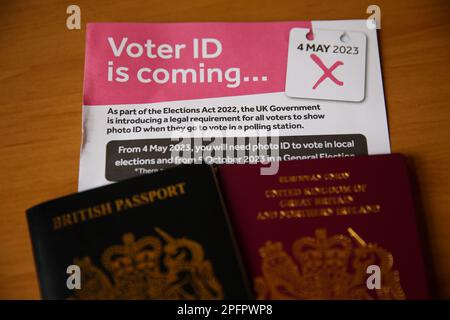 Britische Pässe mit einem Flugblatt, aus dem hervorgeht, dass die Wähler in England bei einigen Wahlen einen Lichtbildausweis vorlegen müssen, um an den Wahllokalen wählen zu können. Stockfoto