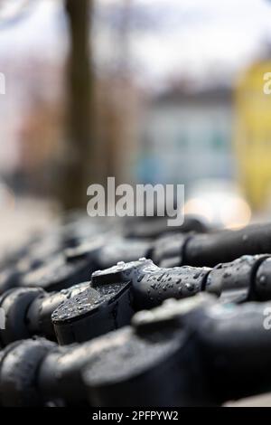 Feuchte Lenker der Elektroroller. Elektrische Roller stehen im Regen auf der Straße. Stockfoto