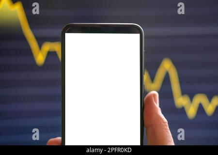 Schwarzes Telefon mit leerem Mockup-Bildschirm auf steigendem Aktiendiagramm. Nahaufnahme-Hand zeigt isoliertes grünes Display des Smartphones. Online-Banking, Nutzung von Fonds-Apps. Fina Stockfoto