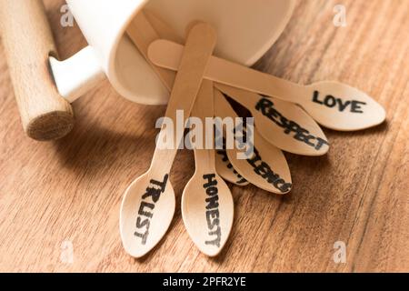 Ein Haufen Holzlöffel aus einer Kaffeetasse jeder Löffel wurde mit Worten wie Liebe, Vertrauen, Geduld, Einfühlungsvermögen, Ehrlichkeit und Respekt auf Holzbasis handgeschrieben Stockfoto