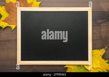 Saubere Tafel auf Holzhintergrund mit Herbstblättern Stockfoto