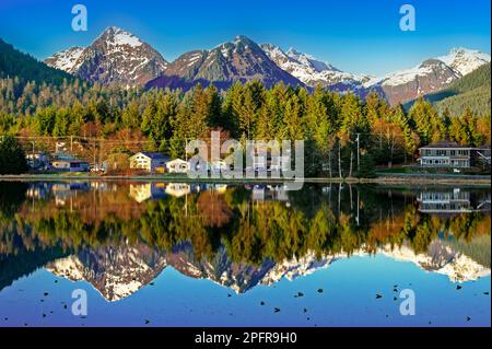 Häuser und Berge, die sich im Frühling in Sitka, Alaska, USA, im Wasser des Schwanensees widerspiegeln Stockfoto