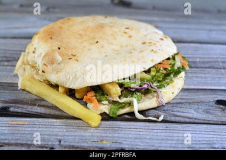 Flat Shami Syrian Bread gefüllt mit pommes Frites und grünem Salat, traditionelle ägyptische frittierte Kartoffeln Finger Sandwich umgeben von kühlen und knusprigen umgeben Stockfoto